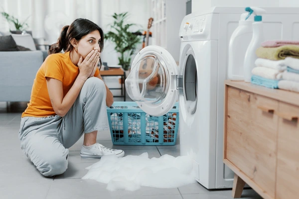 Leaking washing machine causing water damage in a laundry room.